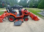 Kubota BX2380 tractor with mower deck, front end loader, and box blade attachments. - Image 2